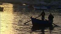 Homens em barcos ao pôr do sol
