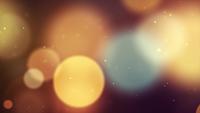 Soft warm bokeh lights of different sizes floating on dark background