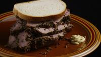 Roterande skott av läckra, premium pastrami-smörgås bredvid en dollop dijon senap - FOOD 033