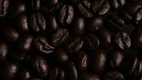Drehender Schuss von köstlichen, gerösteten Kaffeebohnen auf einer weißen Oberfläche - KAFFEEBOHNEN 007