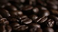 Drehender Schuss von köstlichen, gerösteten Kaffeebohnen auf einer weißen Oberfläche - KAFFEEBOHNEN 025