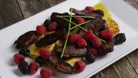 Roterende opname van een heerlijk gerookt spek met eend, gegrilde ananas, frambozen, bramen en honing - FOOD 095