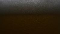 Bier wird in Glas gegossen, wobei der Schaum von Bierglas heruntergeschoben wird