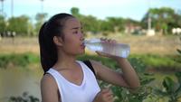 Jovem mulher bebendo água após o exercício