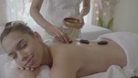 Jonge vrouw met hot stone-massage in de spa