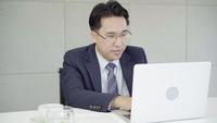 Långsam rörelse - Asiatisk affärsman som arbetar på kontoret med laptop och dokument på sitt skrivbord, konsult advokatkoncept.