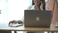 Zeitlupe - lächelnde asiatische Frau der schönen Junge, die an Laptop beim in einem Wohnzimmer zu Hause sitzen arbeitet.