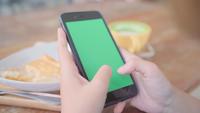Young asian woman using black mobile phone device with green screen.