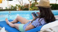 Kvinna använder en mobiltelefon vid poolen
