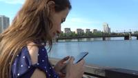 Mulher usando um smartphone perto do rio
