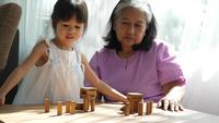 Mormor och barnbarn spelar med Jenga-block