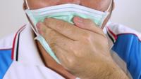 Männer, welche die hygienische Maske husten auf weißem Hintergrund 4K tragen