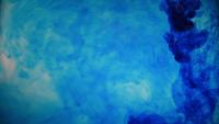 Tinta de tinta de cor azul, derramando sobre o vidro com gotas de tinta caindo e explosão de fumaça abstrata.