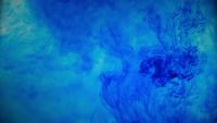 Tinta de tinta de cor azul, derramando sobre o vidro com gotas de tinta caindo e explosão de fumaça abstrata.