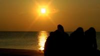 Folk som tittar på solnedgången på stranden
