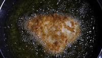 Slow motion of fried chicken in a pan with boiling oil