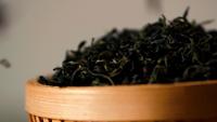 Hojas de té chino secas cayendo al tazón de madera