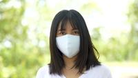 Young Asian woman wearing protective facial mask in the forest