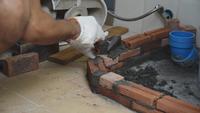 Trabalhador da construção civil está colocando tijolos vermelhos.
